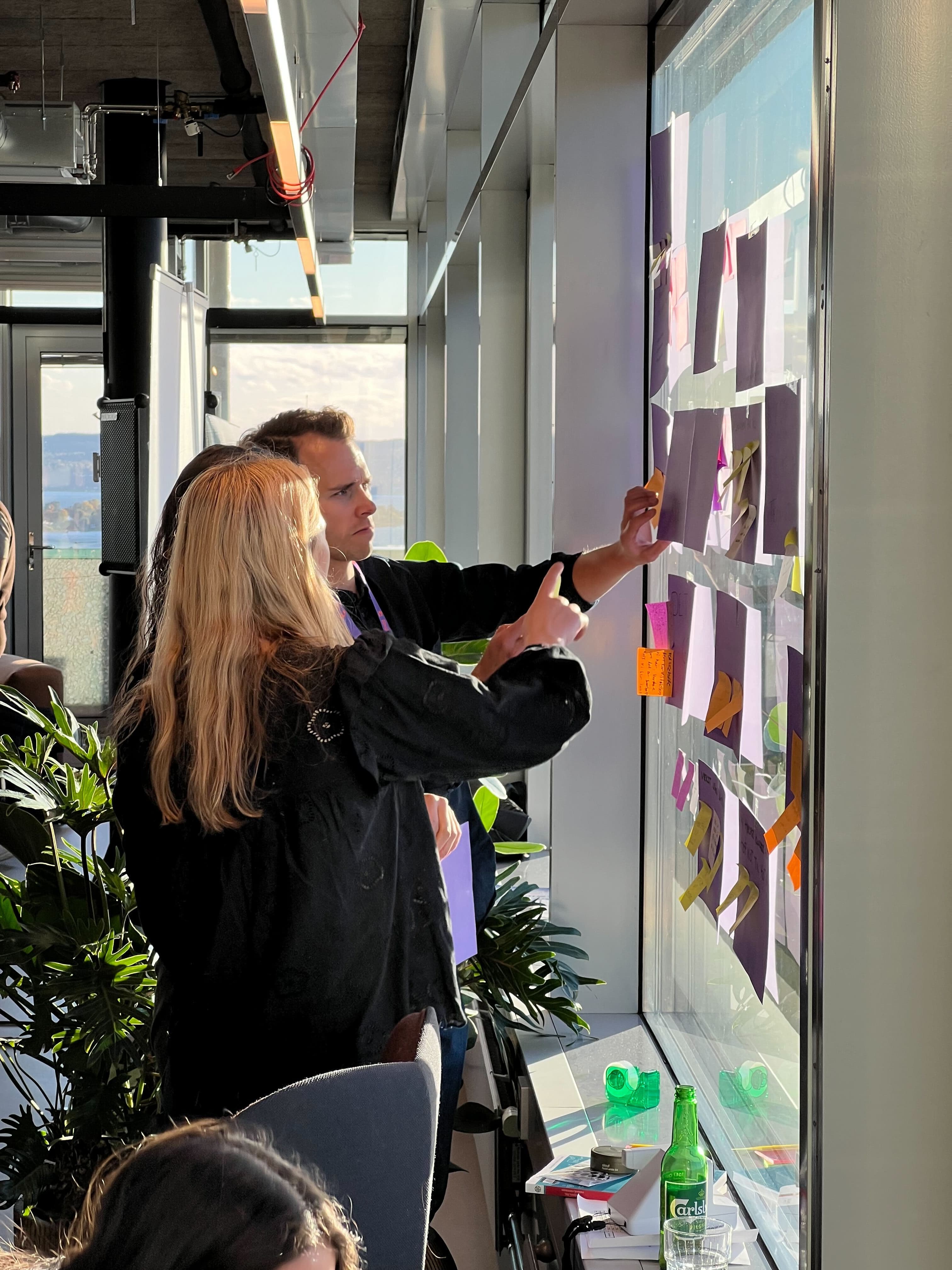 Kollegaer som henger opp store post-its på et vindu.