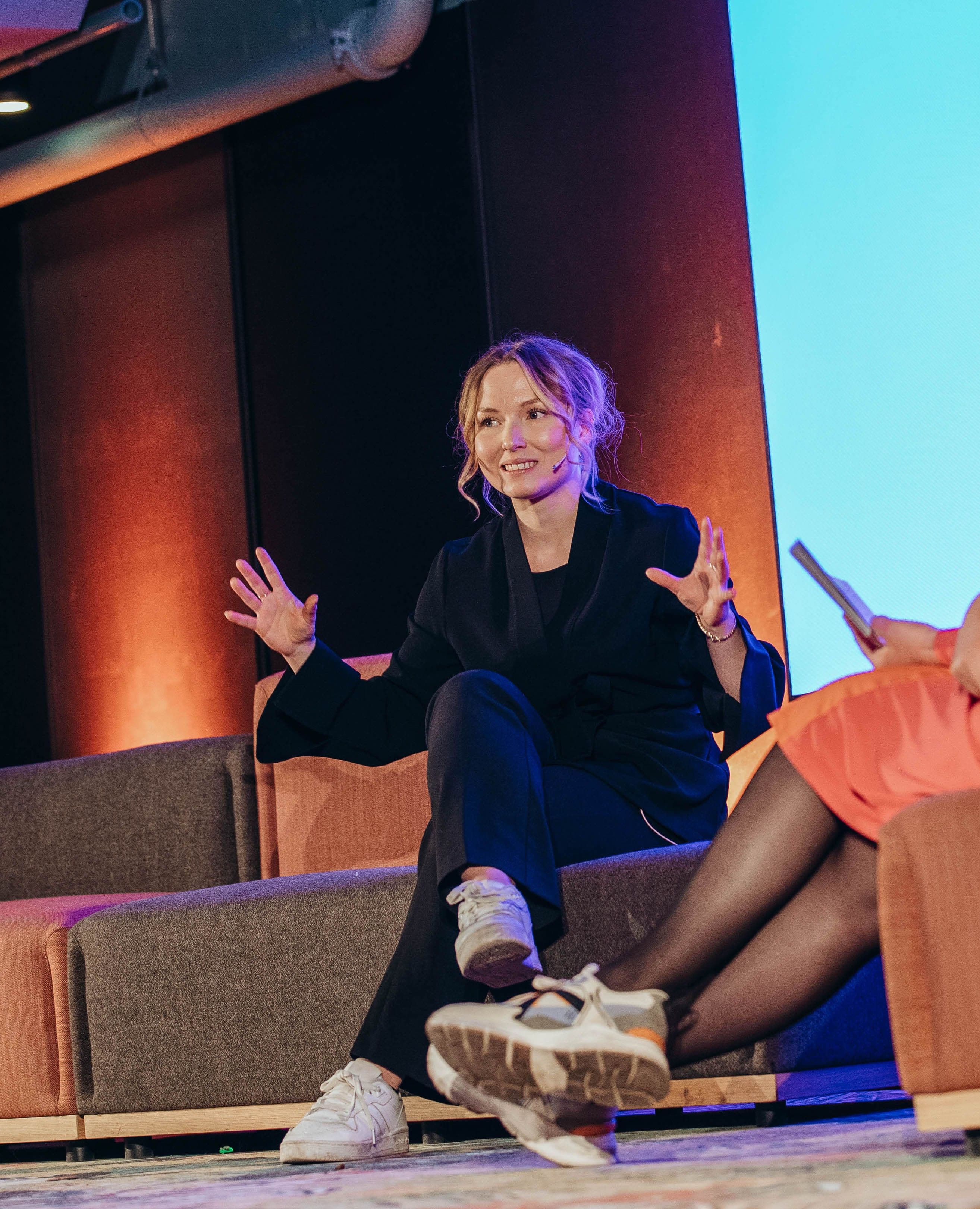 Engasjert designer i paneldebatt på en scene.