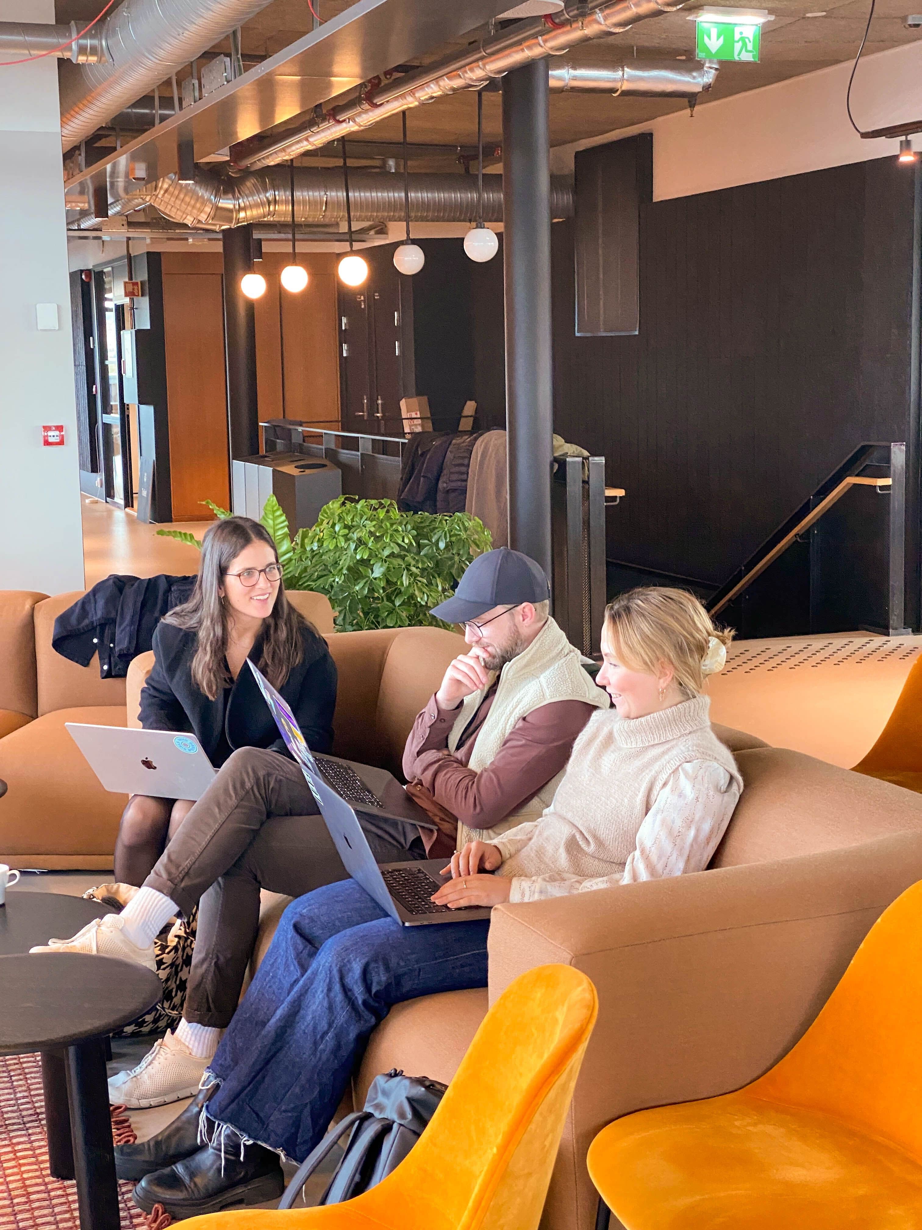 Tre kollegaer som sitter og jobber i en sofa.